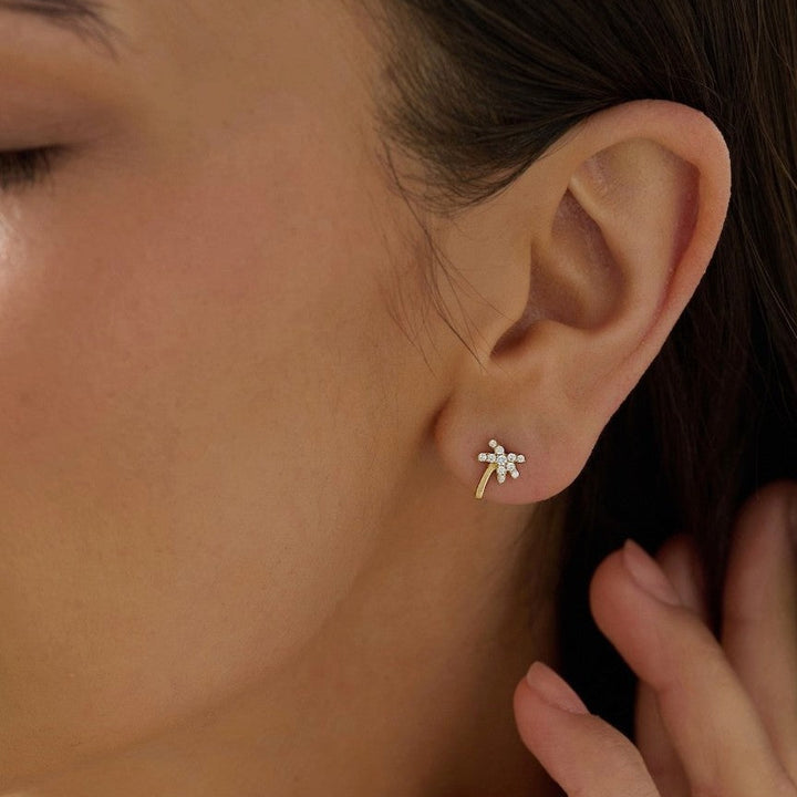 Close-up of an ear wearing a small diamond palm tree stud earring hypoallergenic 