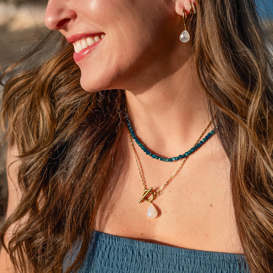model wearing apatite necklace vacation jewelry ocean safe layered with a rainbow moonstone pendant necklace 
