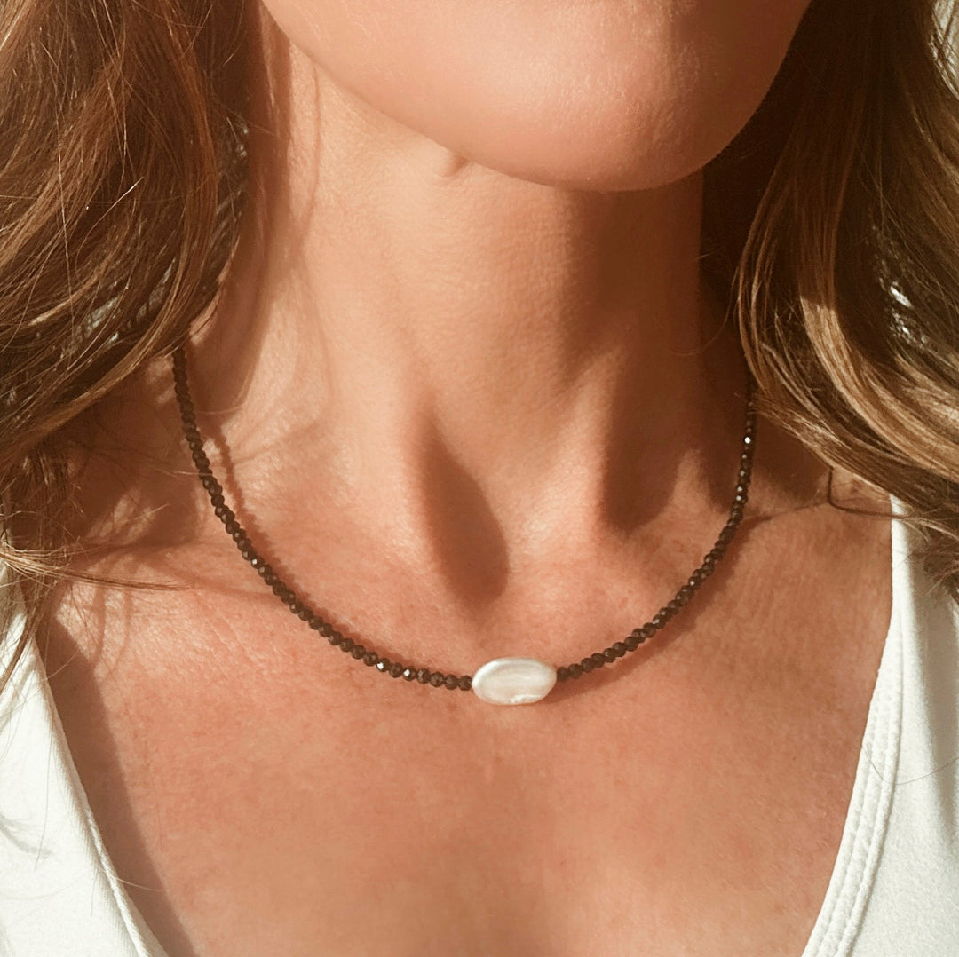 Model wearing a dainty black beaded necklace with a beautiful pearl winter jewelry 