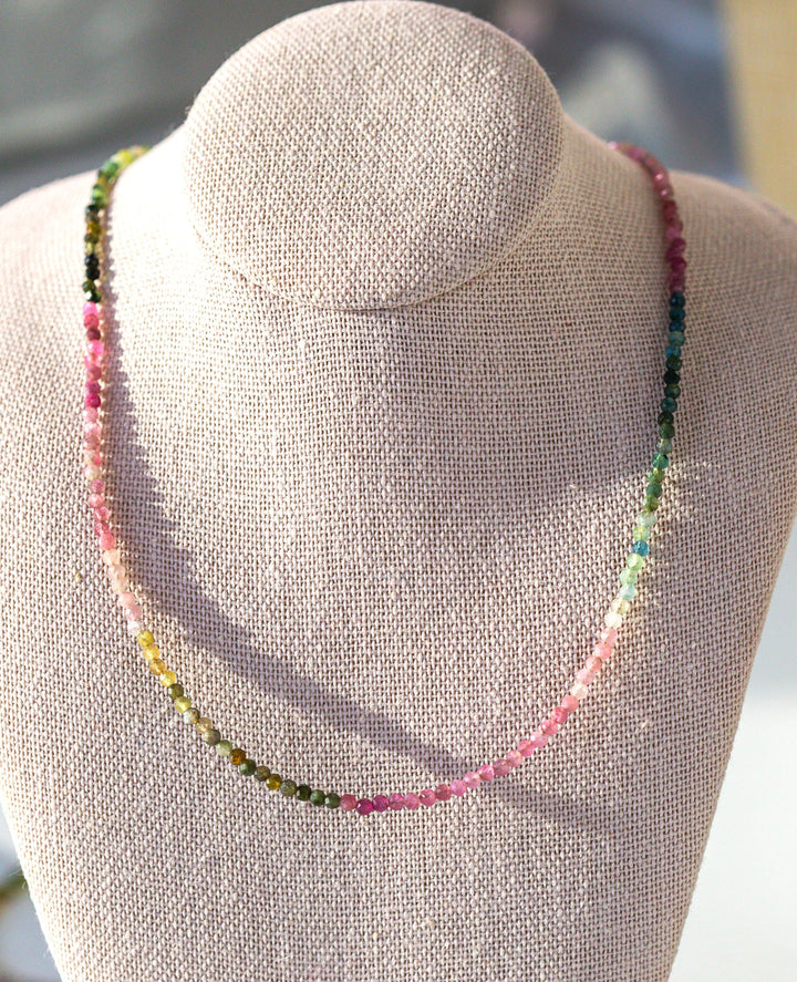 Necklace with multicolored beads on a gray mannequin bust.