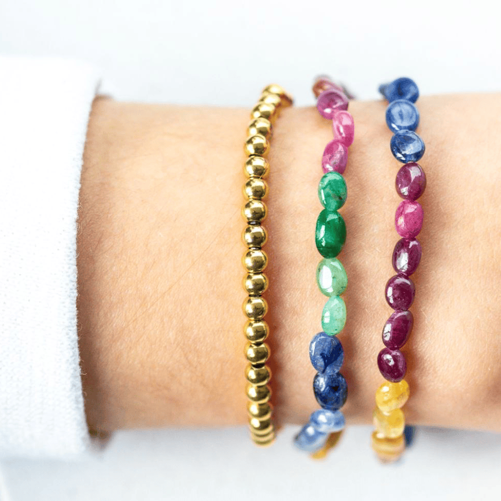 Set of colorful genuine AAA Sapphire beaded bracelets on a wrist against a white background