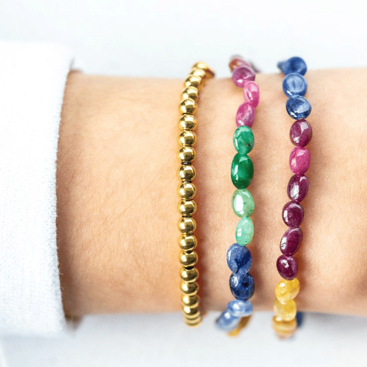 Set of colorful genuine AAA Sapphire beaded bracelets on a wrist against a white background