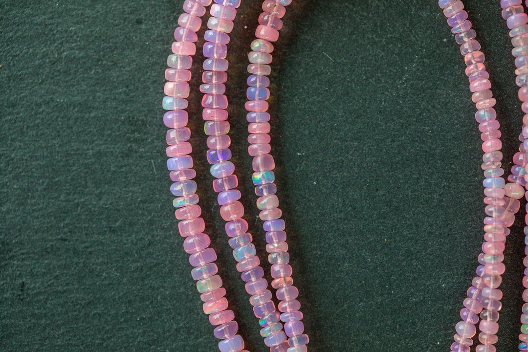 Close-up of a strand of small, multicolored beads on a dark green background