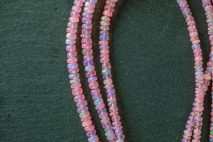Close-up of a strand of small, multicolored beads on a dark green background
