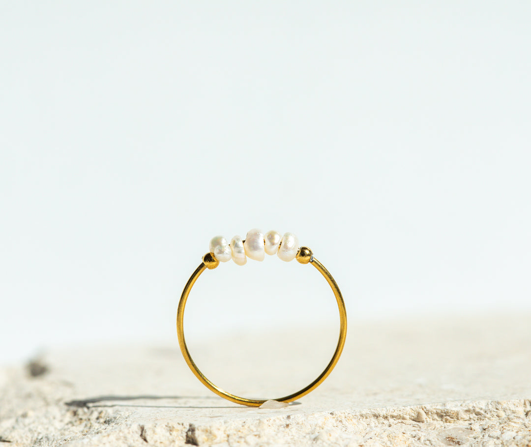 Gold ring with pearls on a light background