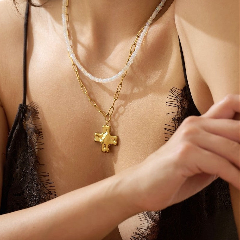 Close-up of a person wearing a gold big cross necklace pendant.
