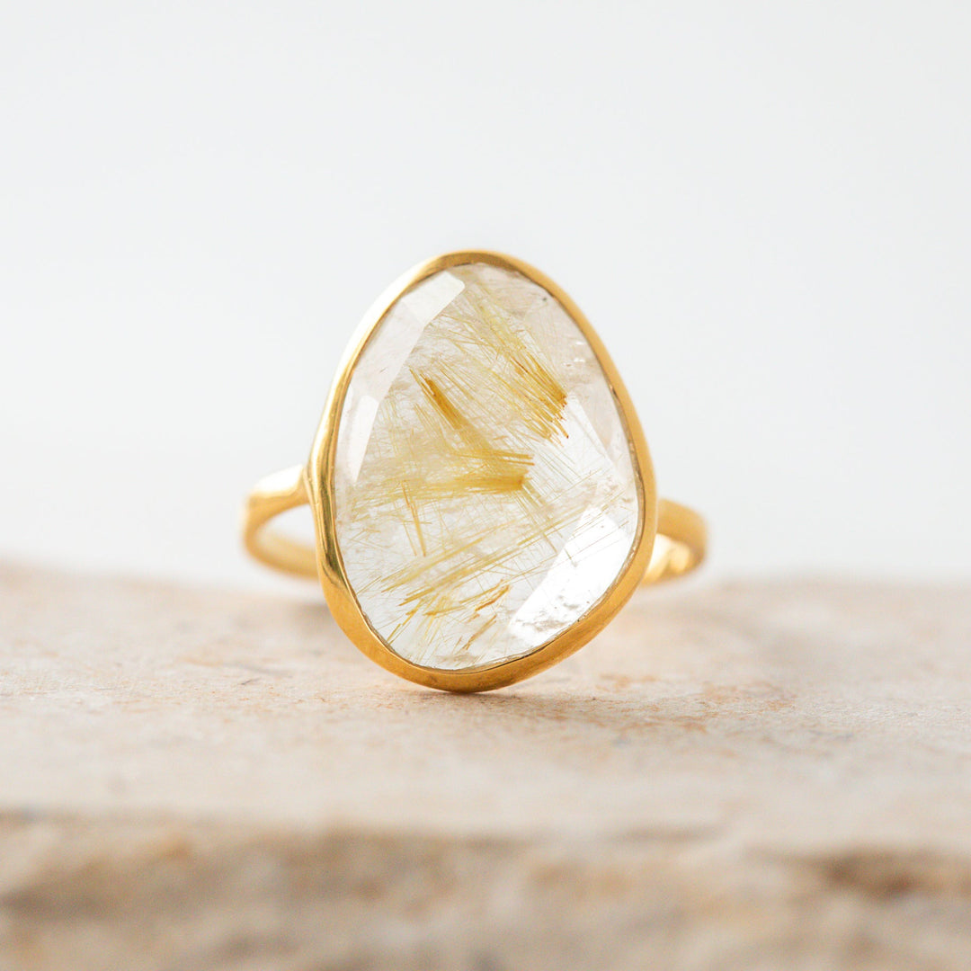 Large Gold faceted gemstone ring with beautiful stone on a light wooden surface