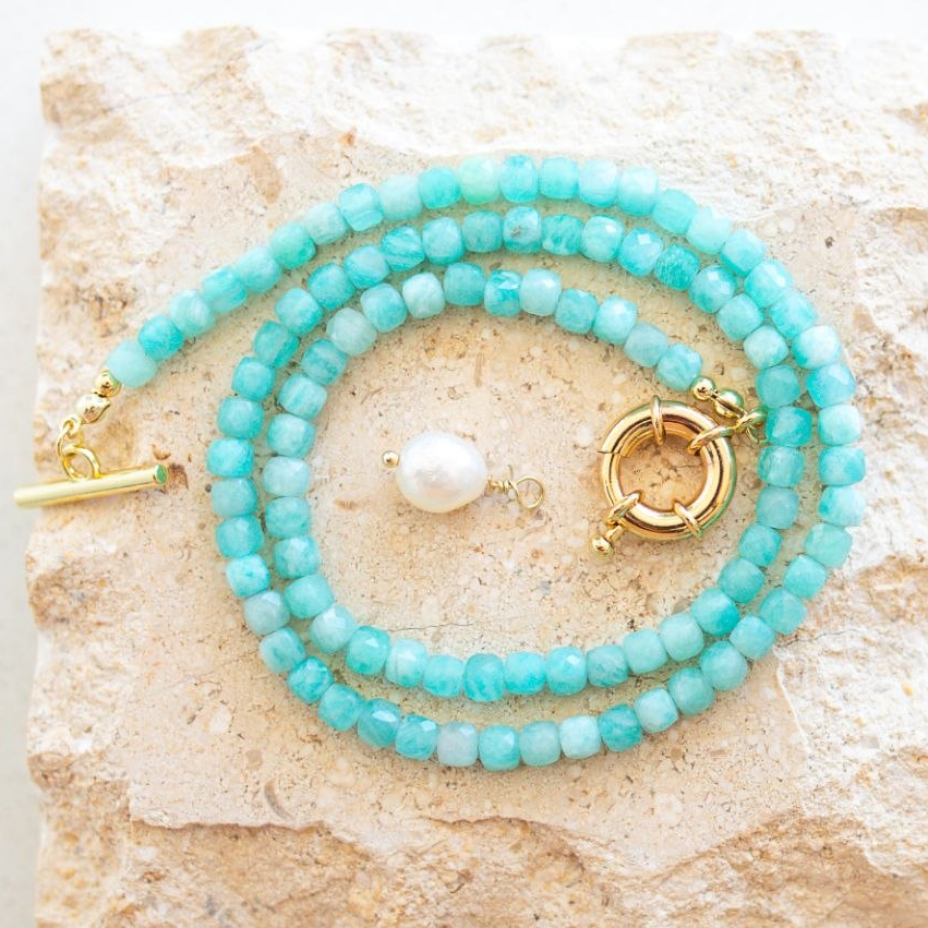 Turquoise beaded bracelets with gold clasps on a textured stone surface