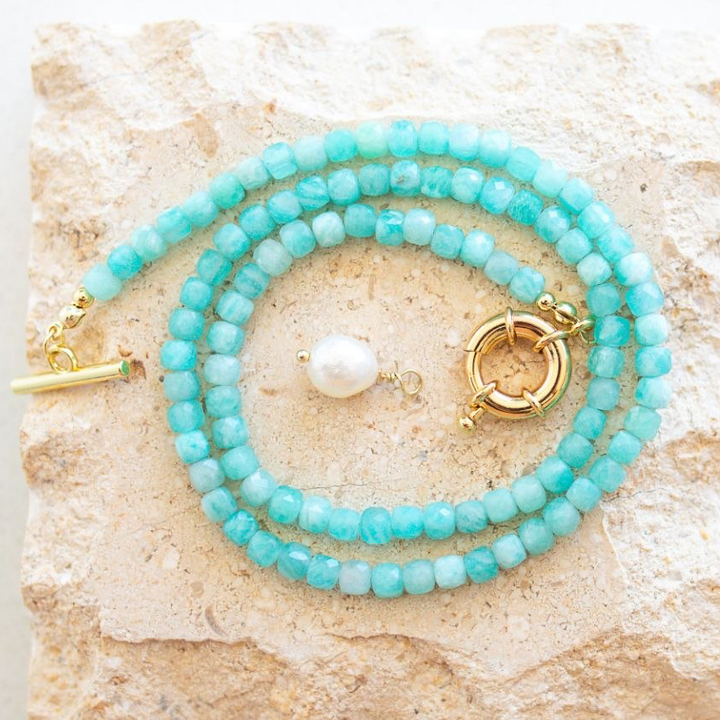 Turquoise beaded bracelets with gold clasps on a textured stone surface