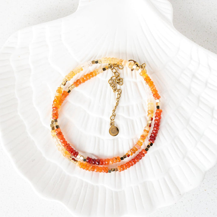 Close up of faceted fire opal rondelle beads graduating from golden yellow to burnt orange