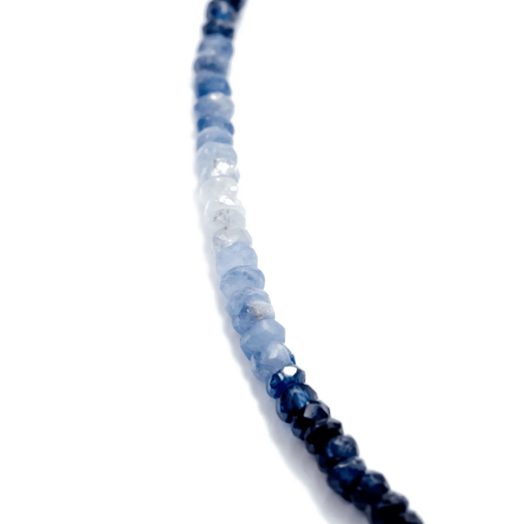 Close-up of a necklace with blue and white AAA Sapphire beads on a white background