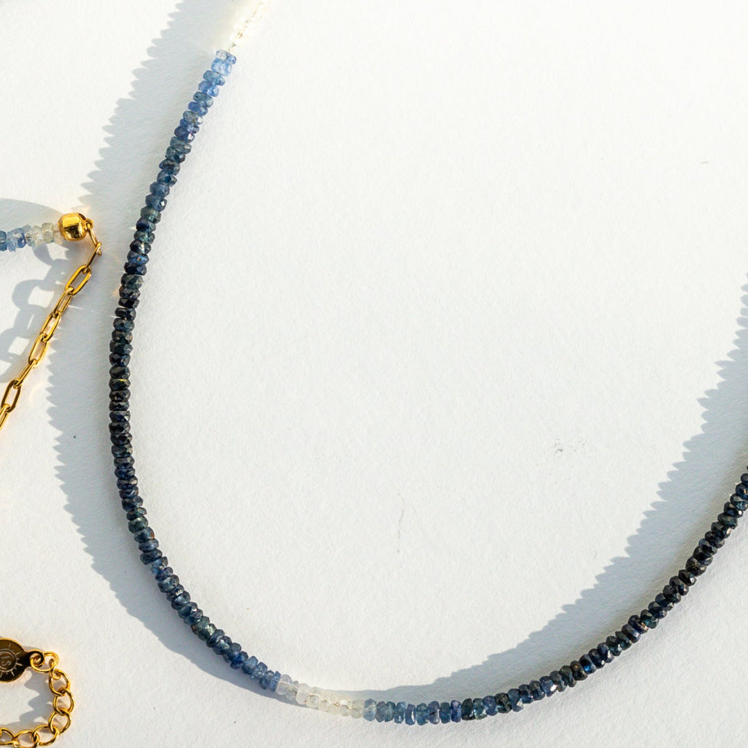 Close-up of gold and blue beaded necklaces on a white background