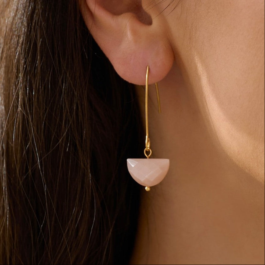 Close-up of an ear wearing a gold threader earring with a pink moonstone waterproof gold real stone.