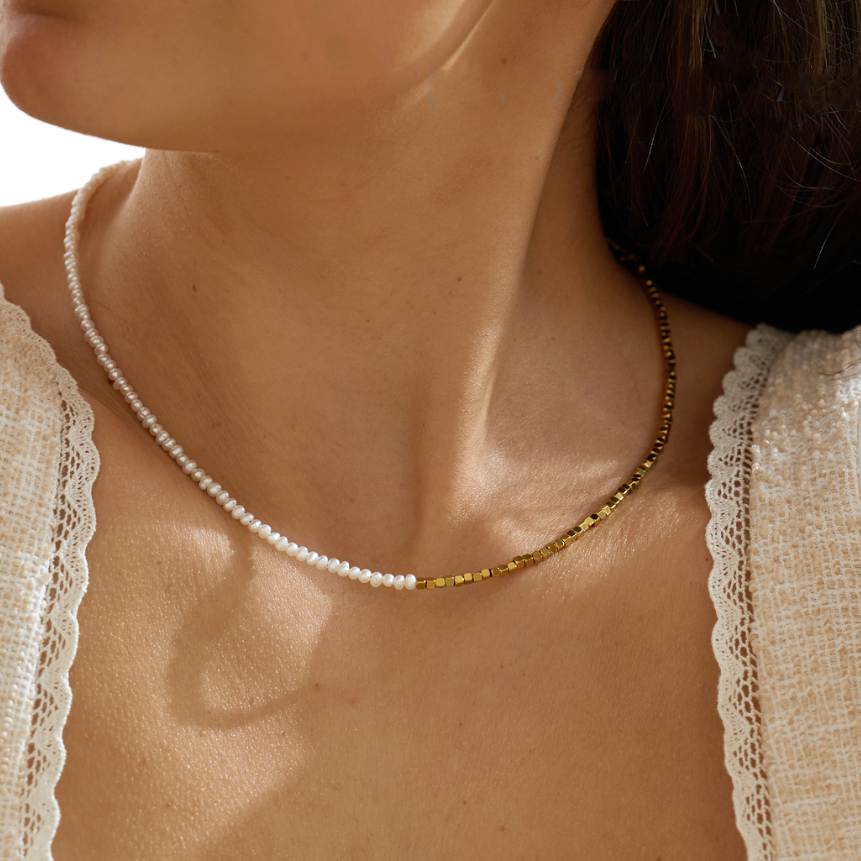 Close-up of a beautiful model wearing a delicate pearl beaded necklace with a textured top.