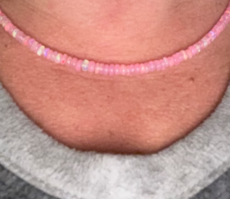 Close-up of a person wearing a pink fire opal beaded necklace.