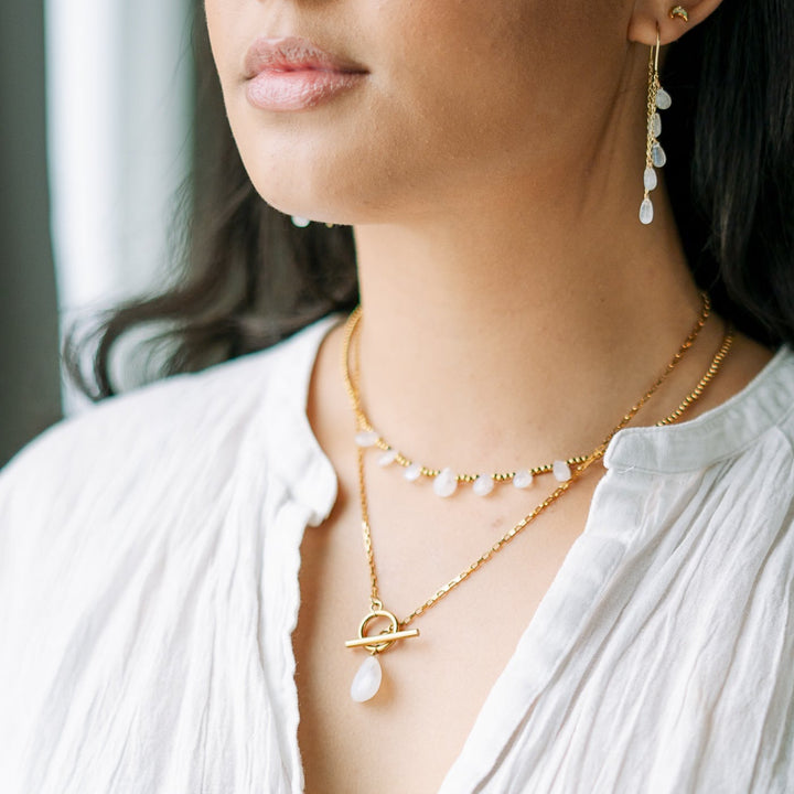 Close-up of a woman wearing gold necklaces and earrings with a blurred background