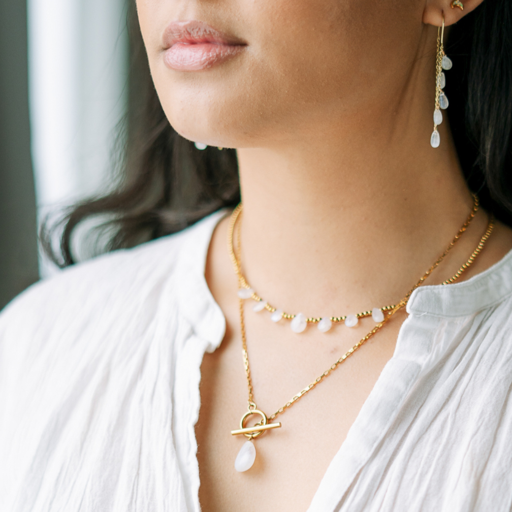 Woman wearing a white blouse with Moonstone Toggle necklaces and moonstone dangle earrings.
