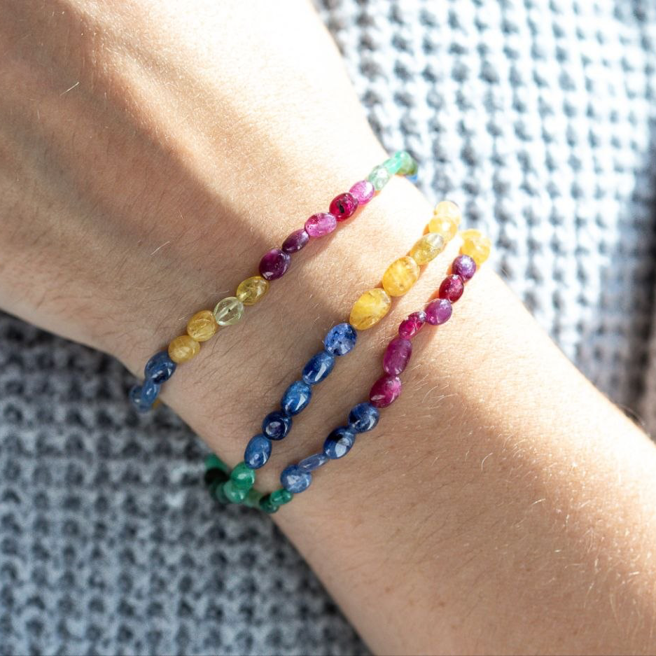 Multicolored Genuine Sapphires beaded bracelets on a wrist with a blurred background