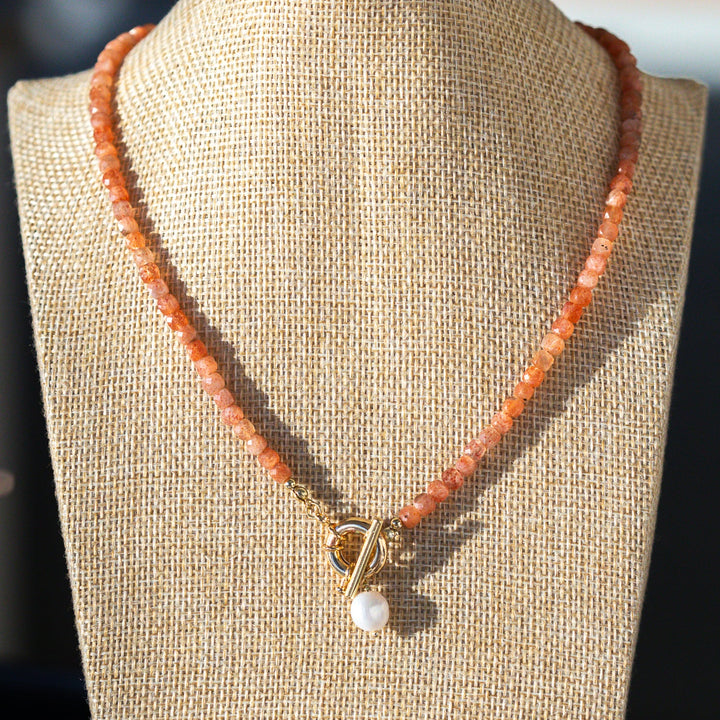 Earthy Peach Beaded Necklace with a pendant on a mannequin bust against a neutral background