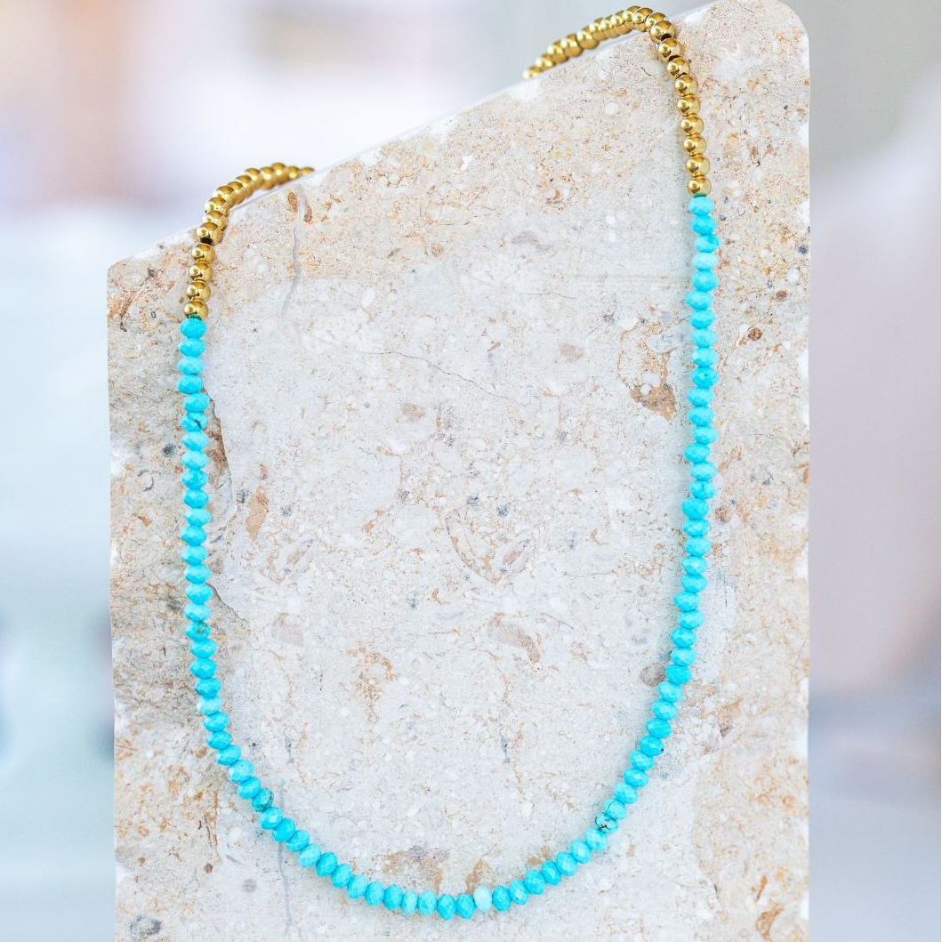 Turquoise beaded necklace on a stone surface with a blurred background