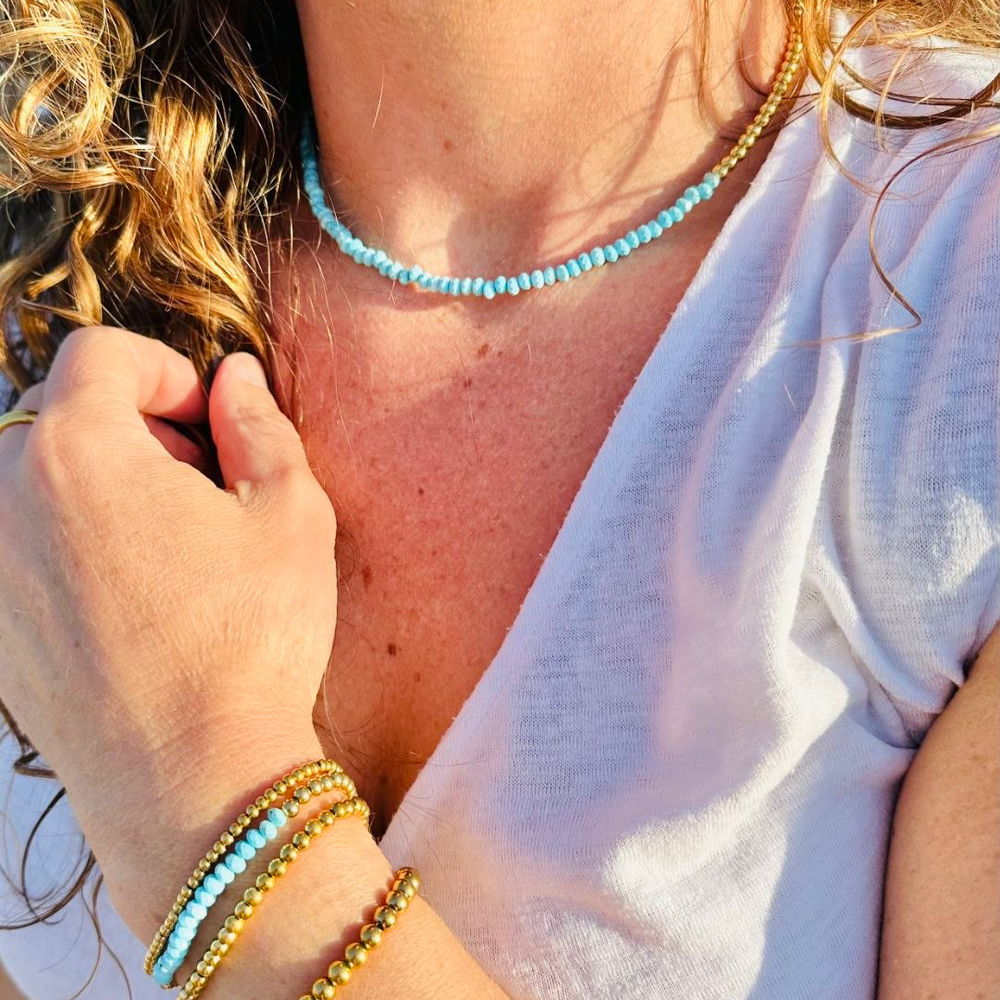 Close-up of a person wearing a necklace and bracelets with a blurred background