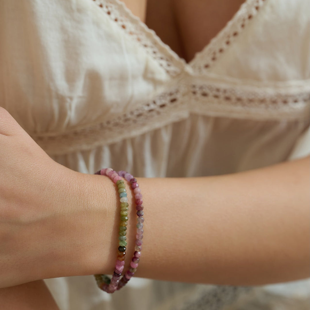 Close-up of a person wearing a gemstone beaded watermelon tourmaline beautiful bracelet on a blurred background