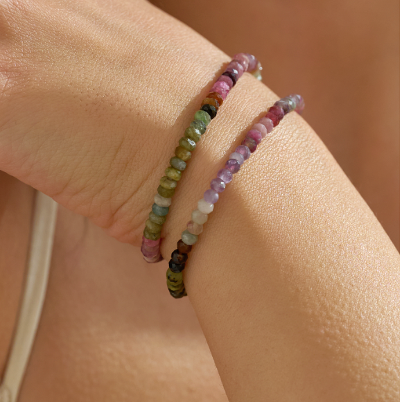 Multicolored october birthstone gift for her tourmaline beaded bracelet on a wrist against a neutral background
