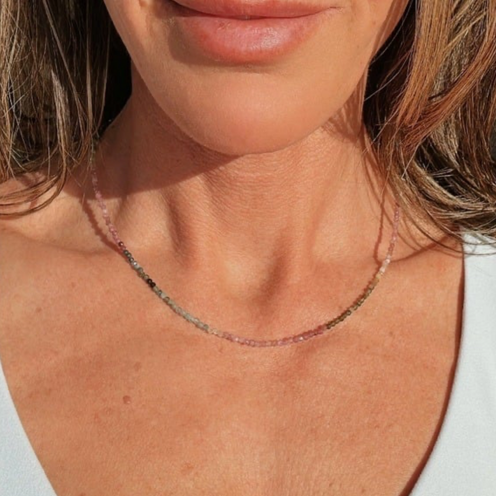 Close-up of a beaded colorful necklace on a person with a white background