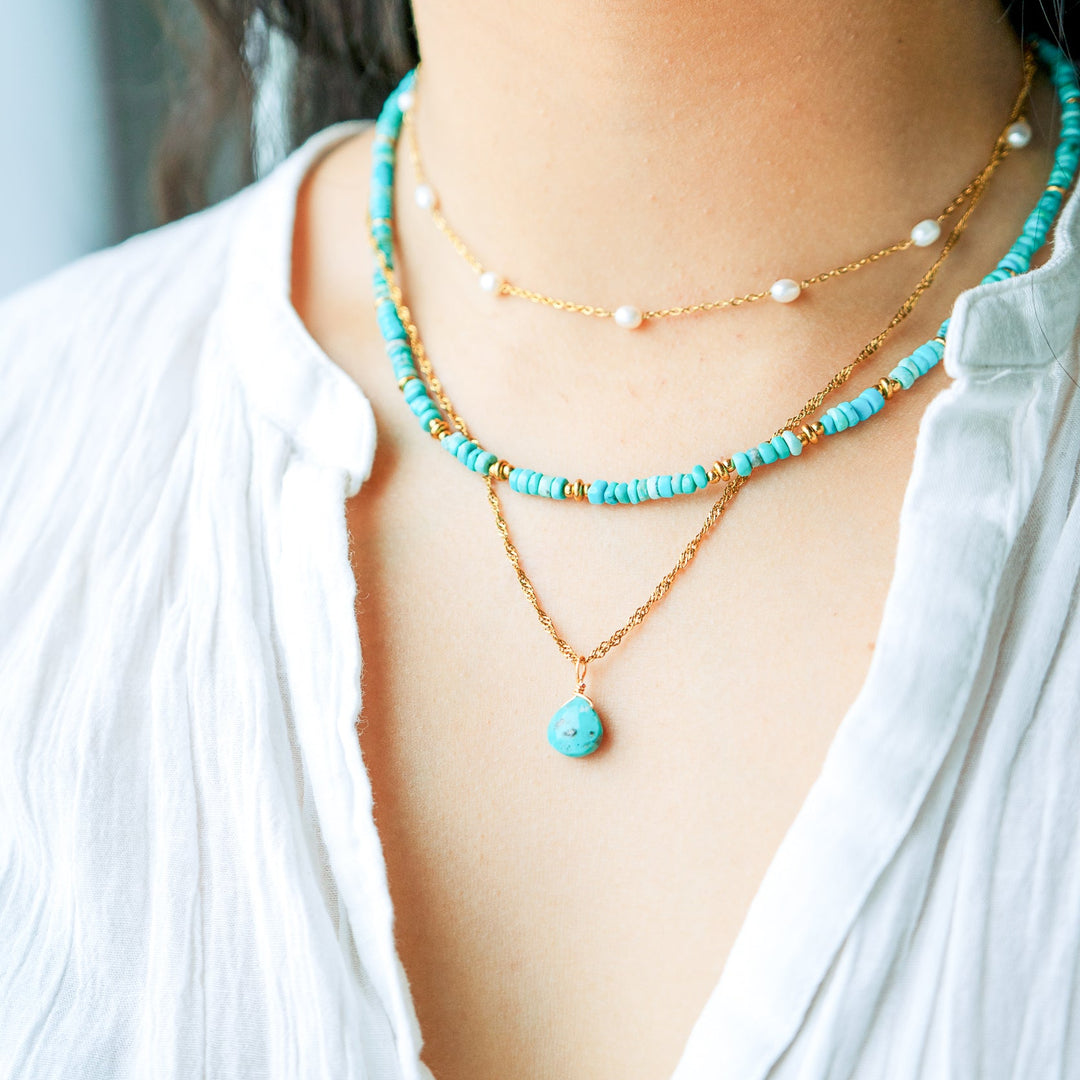 Necklace with turquoise beads and gold chain worn by a person